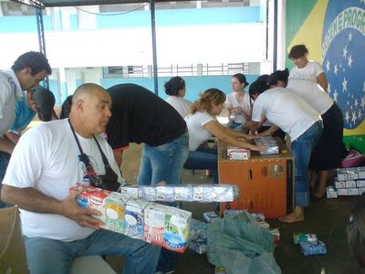 foto de pessoas trabalhando com as caixas de leite, passando fita adesiva e colando-as